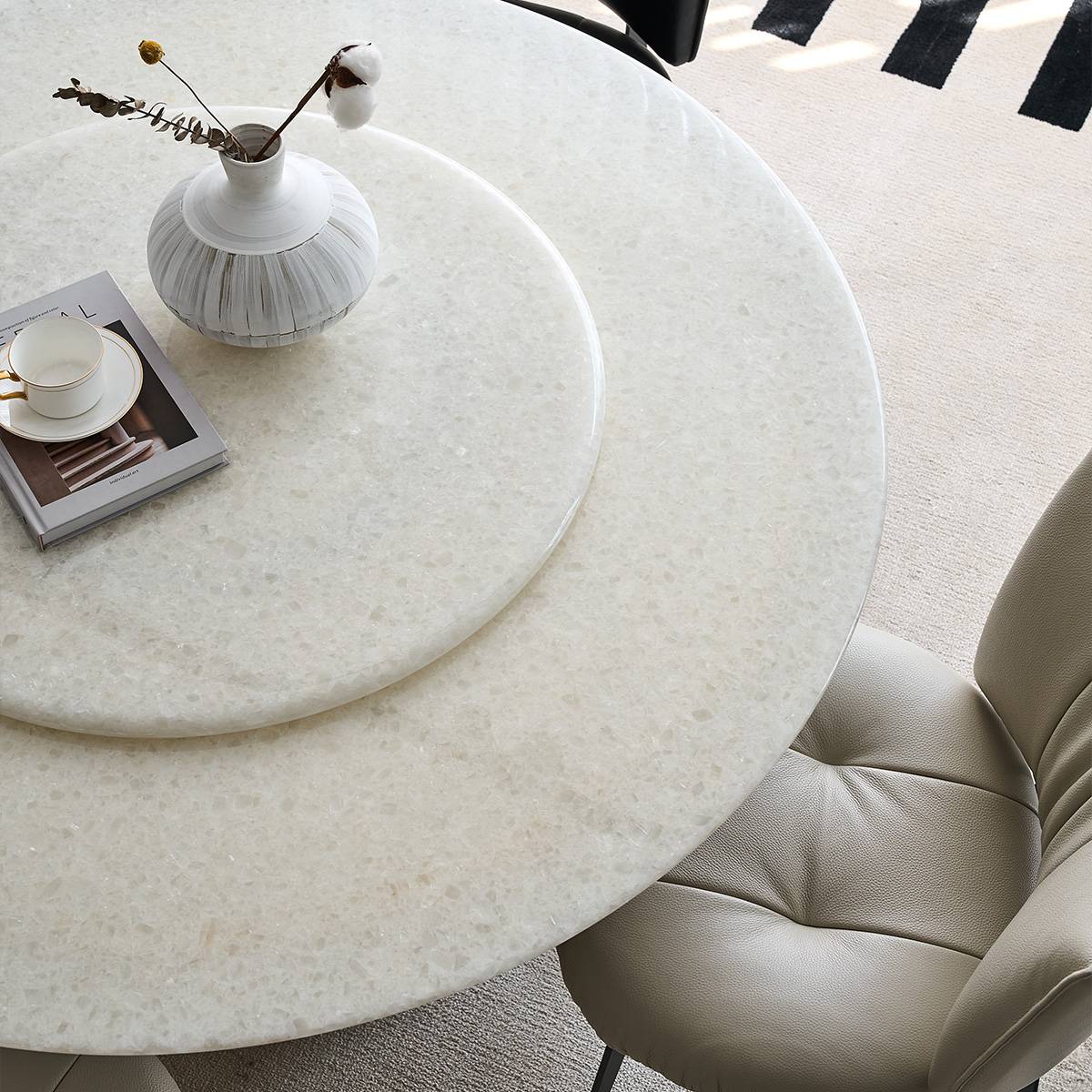 Top-down view of the round dining table showing the rotating tray, book, and vase styling