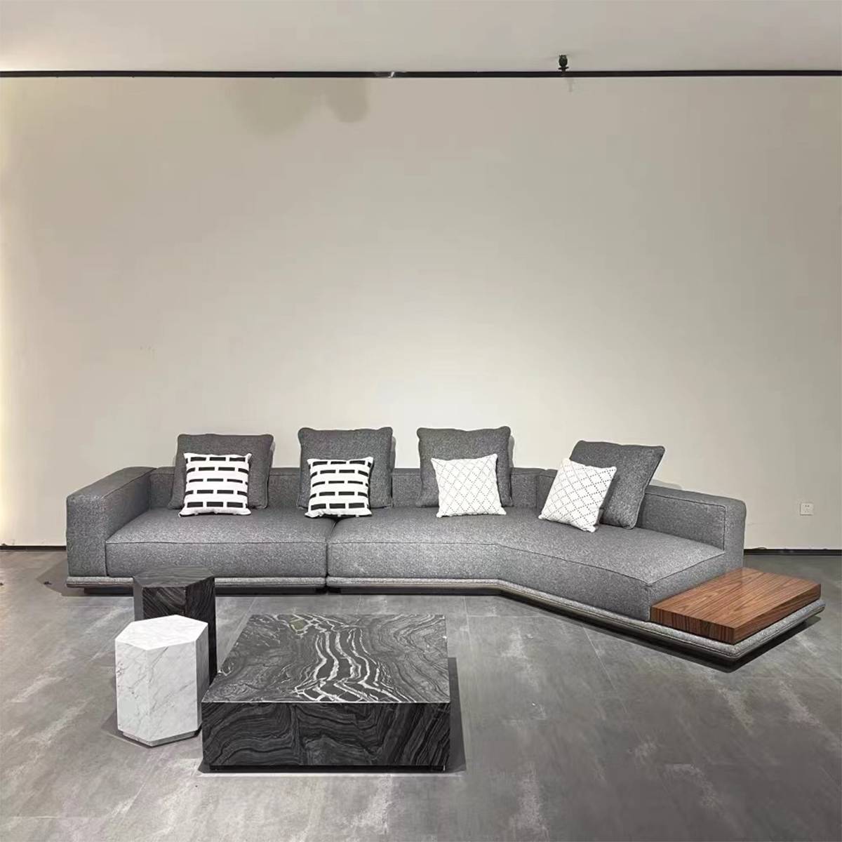 Front view of the sofa showing the grey fabric, patterned throw pillows, and the integrated wooden side table.