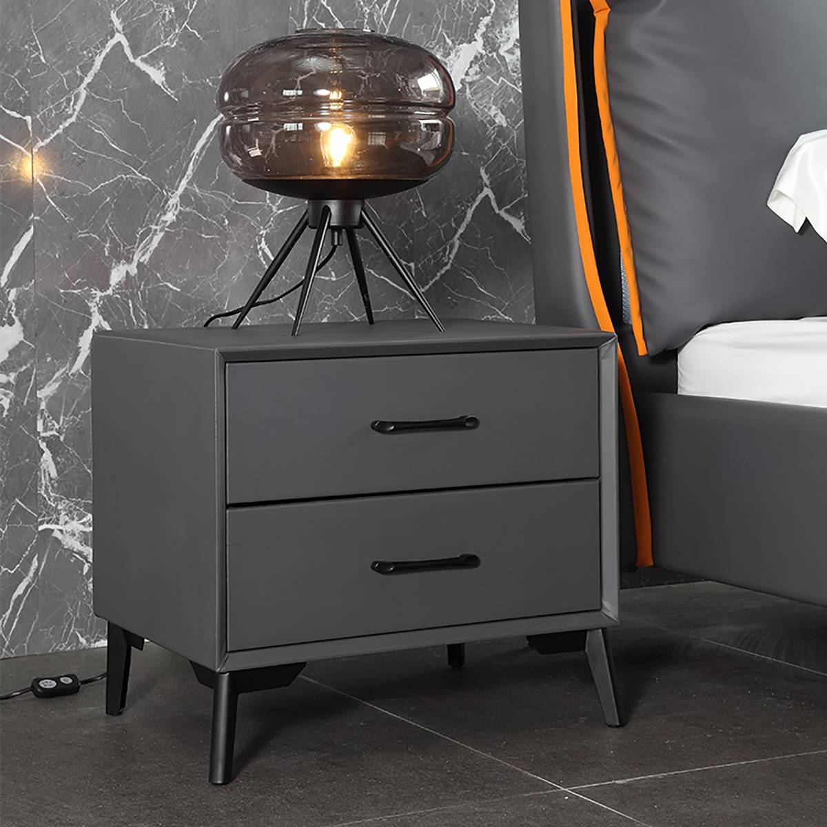 Close-up of the bedside cabinet next to a bed with orange accents