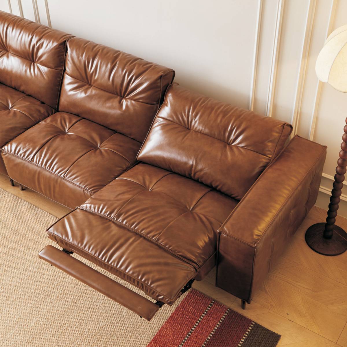Side view of a brown leather functional sofa with the recliner extended, showing the mechanical linkage and tufted backrest.