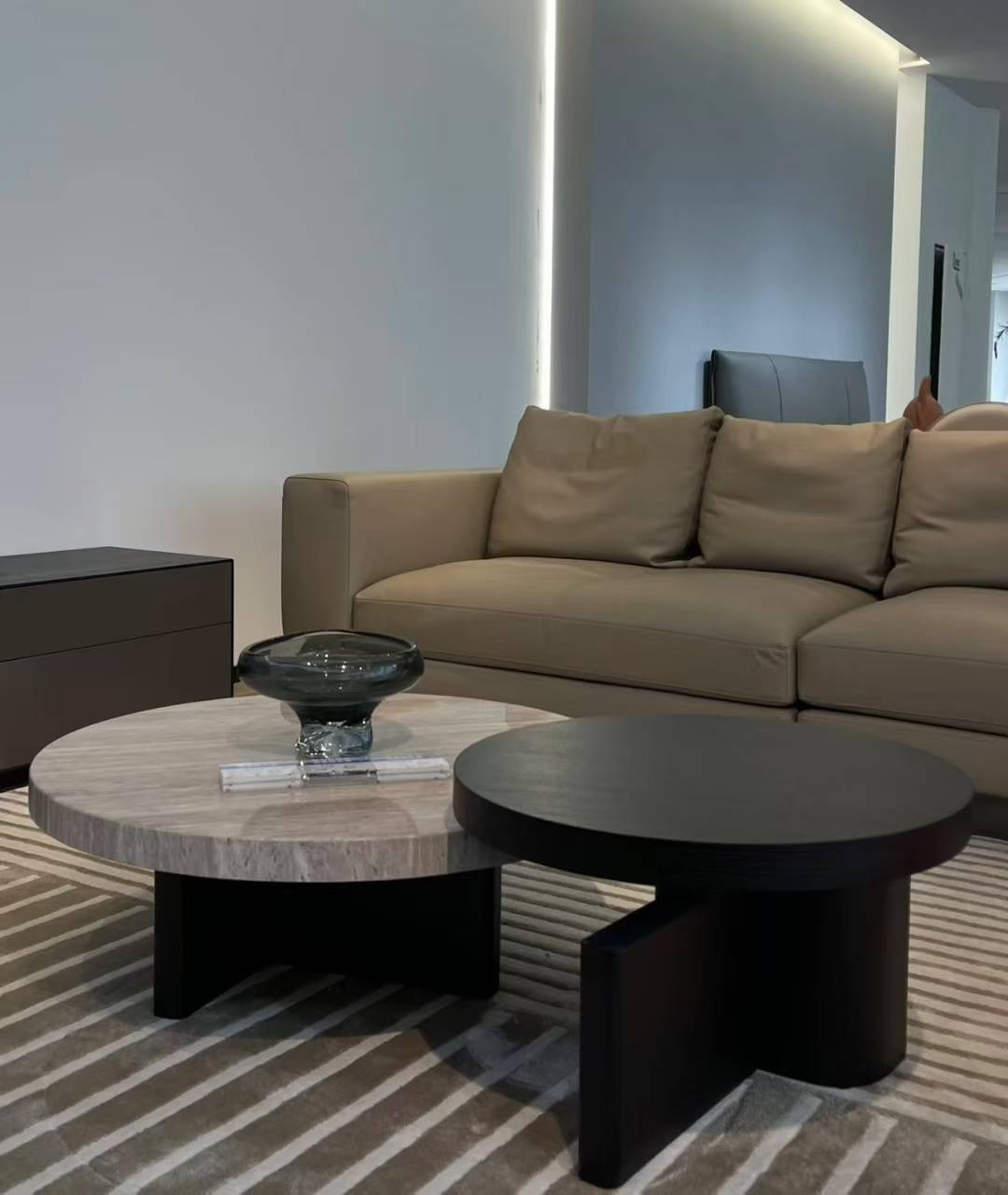 Close-up view of the nesting coffee tables showing the travertine and black wood textures