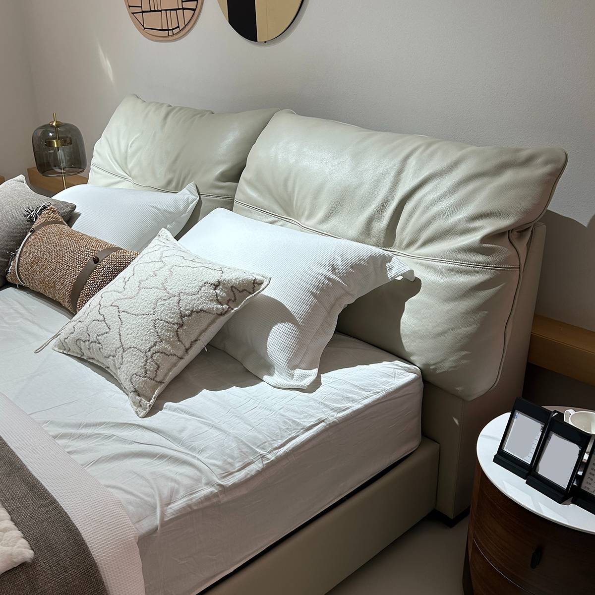 Close-up view of the cream-colored leather headboard with down pillows and white bedding