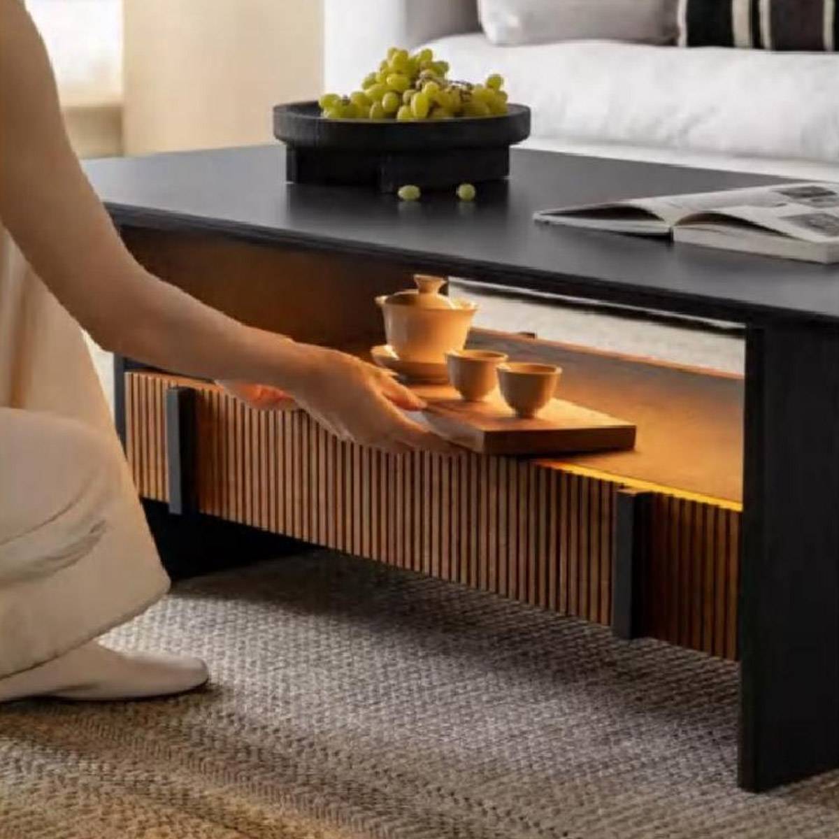 Close-up of a hand placing a tea tray into the lower shelf of the coffee table