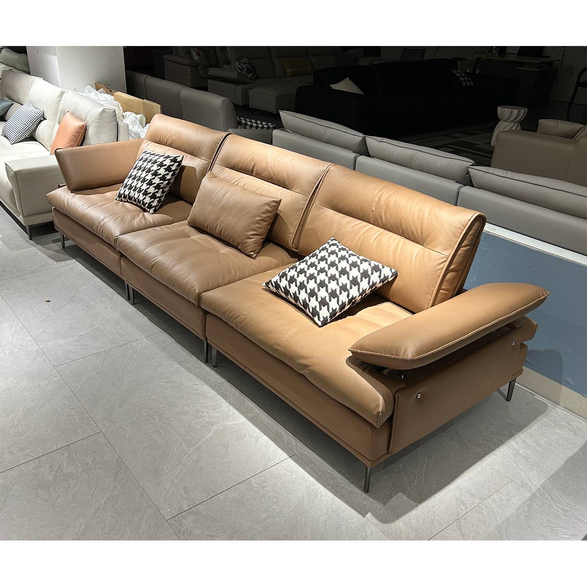 Side angle view of the brown leather sofa with patterned throw pillows