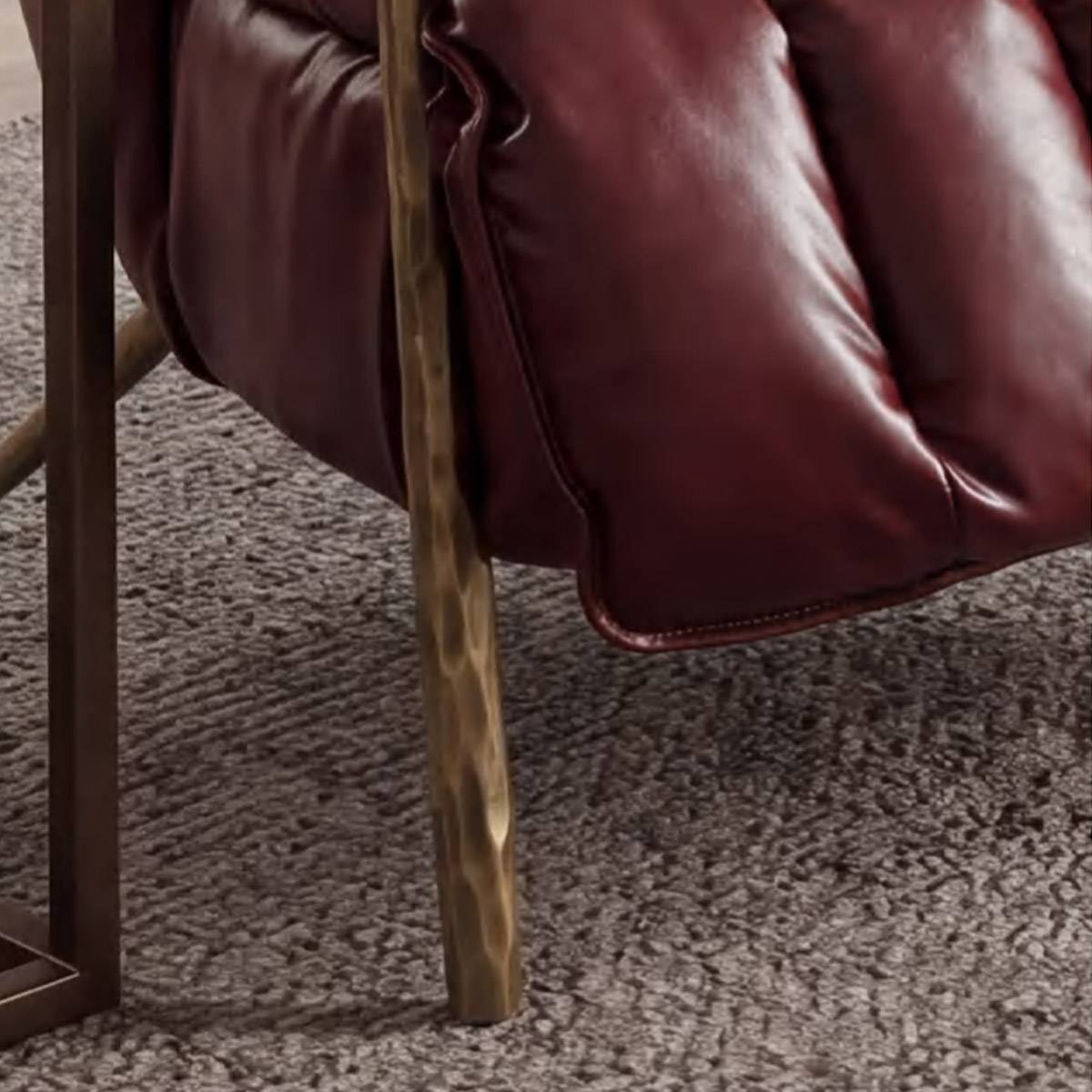 Close-up detail of the hammered metal leg and leather upholstery stitching