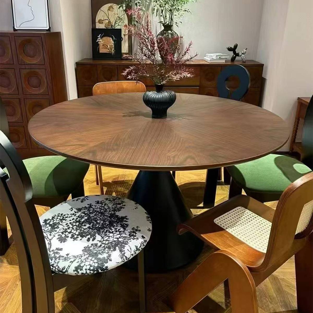 Close-up of the round walnut dining table with a black vase centerpiece