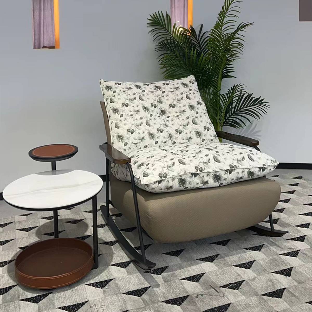 Front view of the rocking lounge chair with floral cushions next to a side table