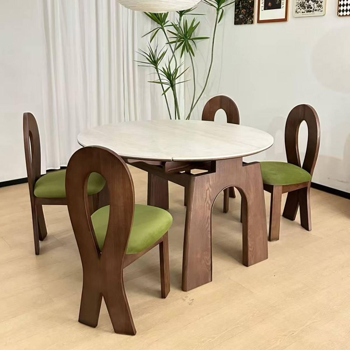 Round dining table with white stone top and walnut wood base, surrounded by four chairs with green seats