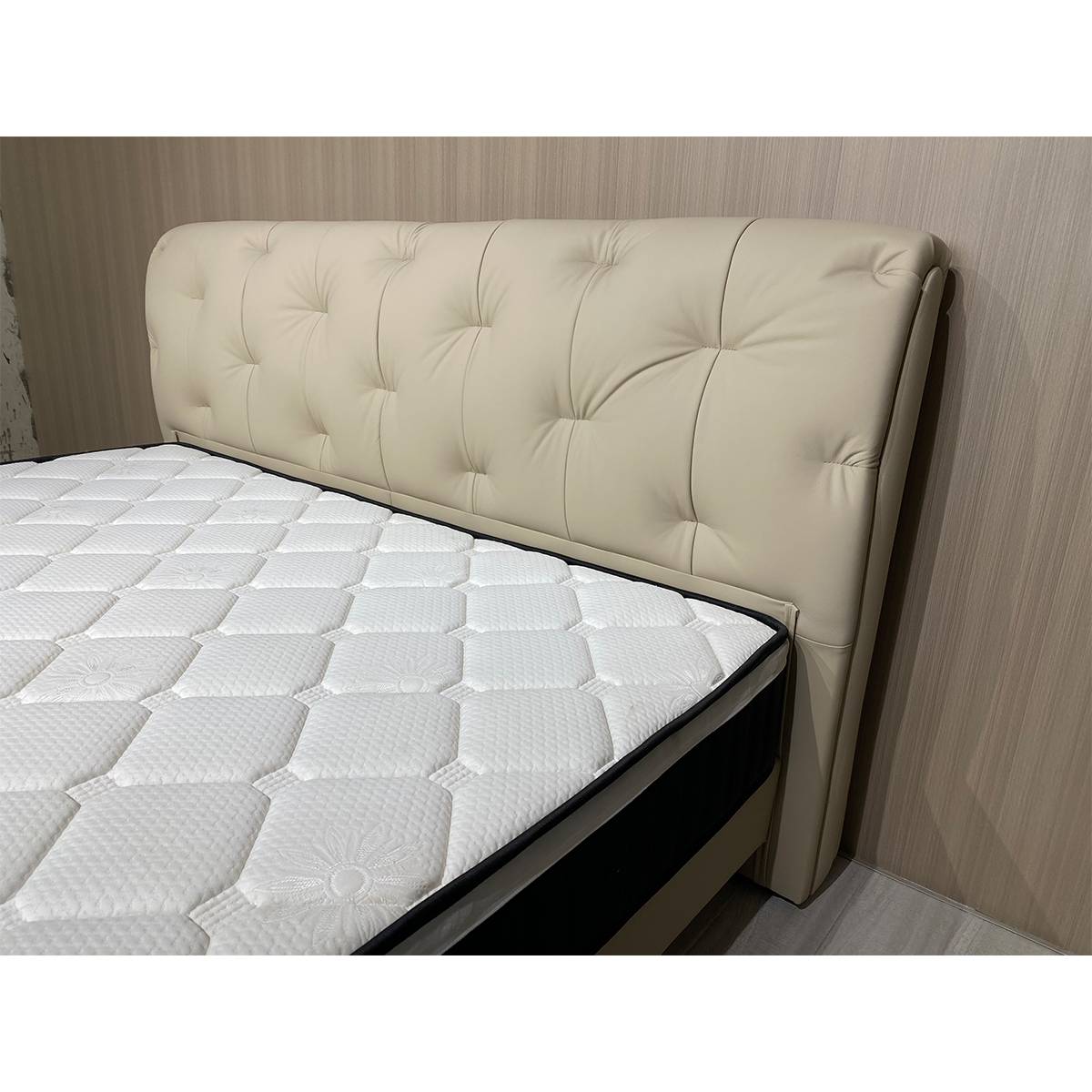 Side view of the beige tufted leather bed headboard and mattress