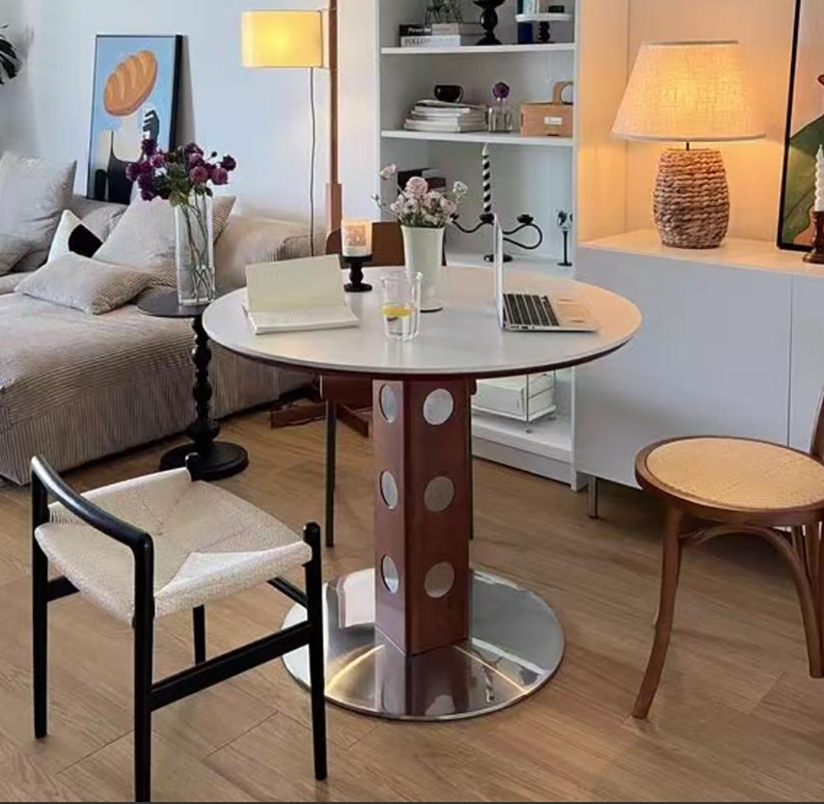 White round dining table with a laptop and flowers in a living room setting
