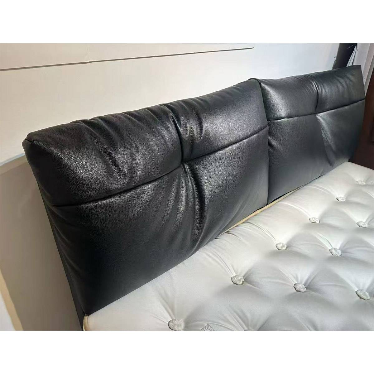 Close-up view of the black leather headboard and white tufted mattress base of the Ocean Wave bed