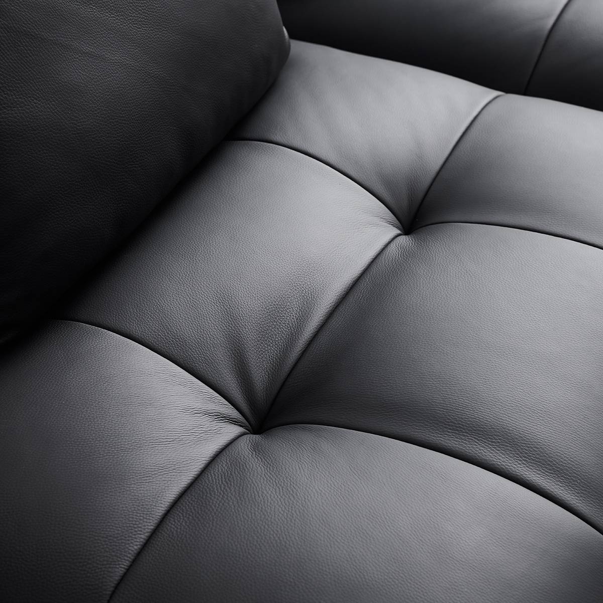 Close-up view of the black leather texture and tufted stitching on the sofa seat