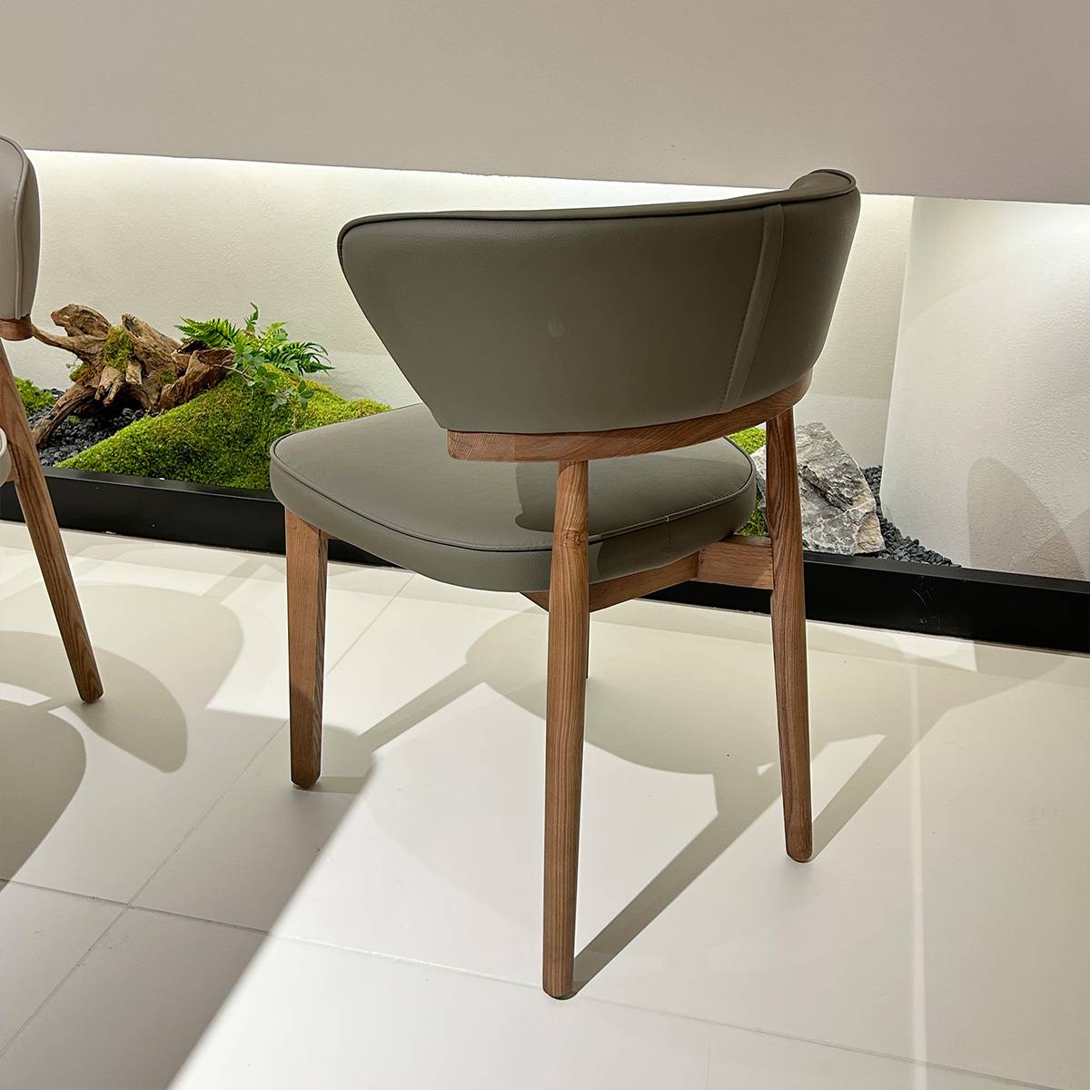 Rear side view of a grey dining chair showing the backrest curve