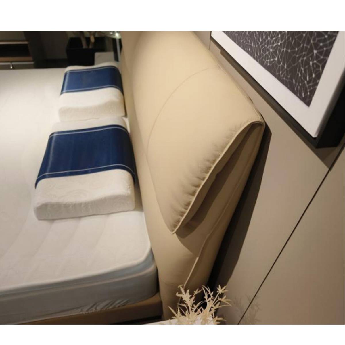 Close-up detail of the beige leather headboard and pillows on the bed.