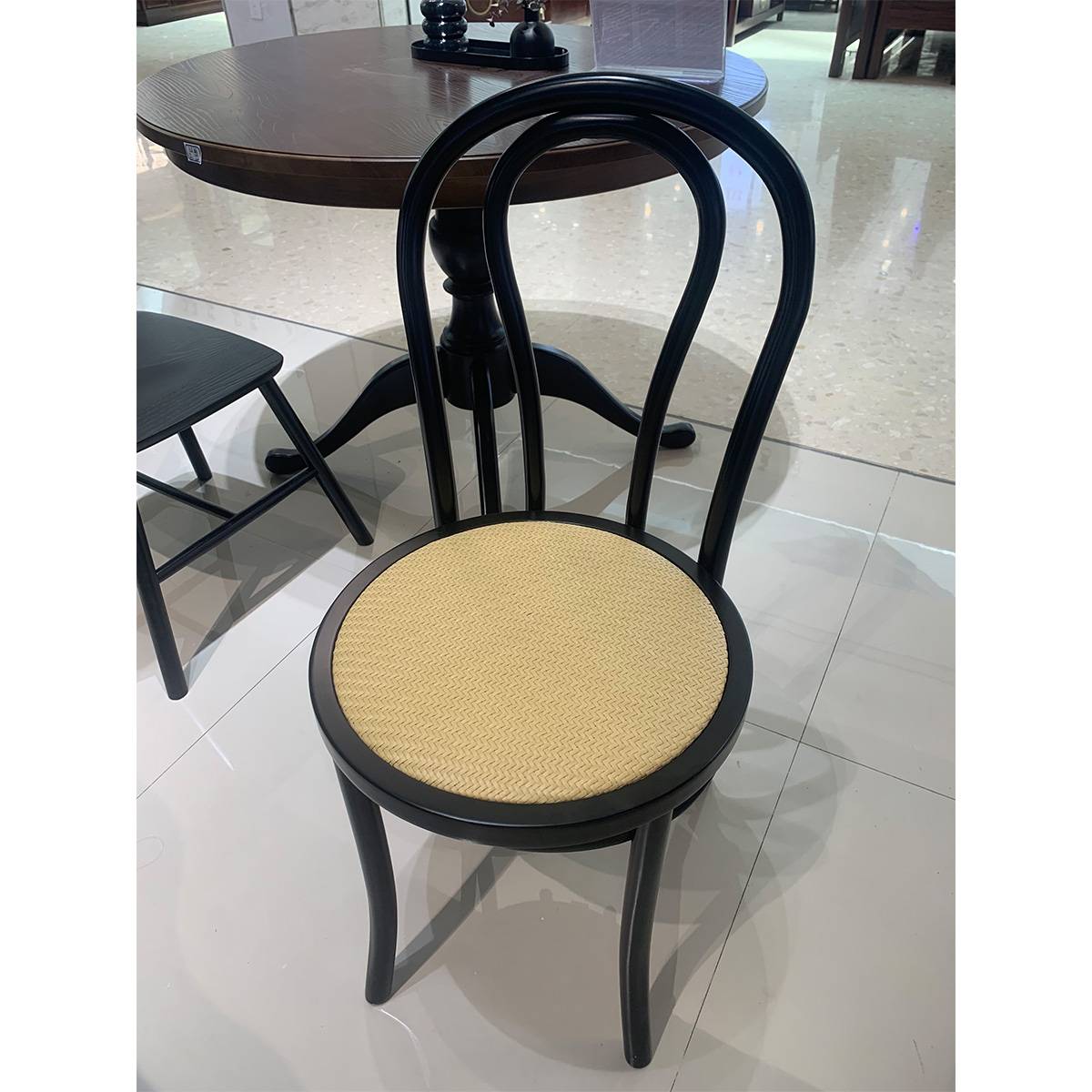 Close-up of a black mid-century dining chair with a woven seat.