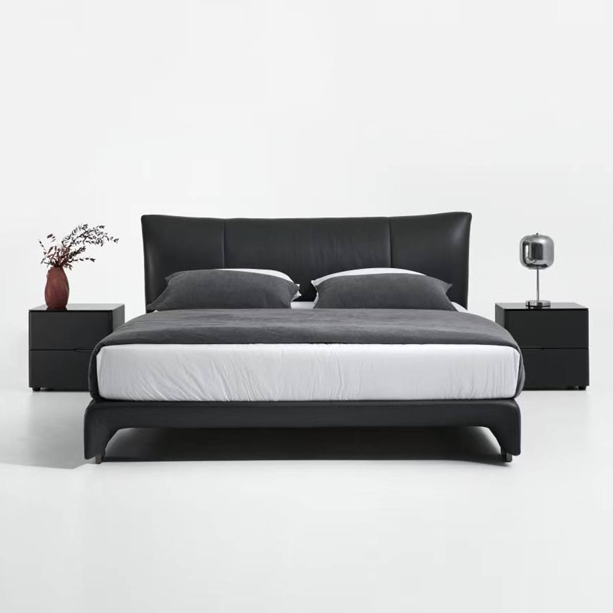 Front view of the black leather bed showing the headboard and footboard design.