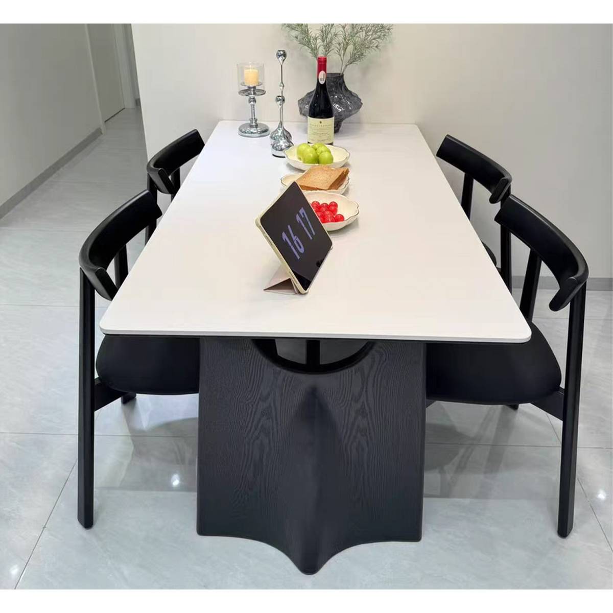 Front view of white dining table with black base, set with tableware