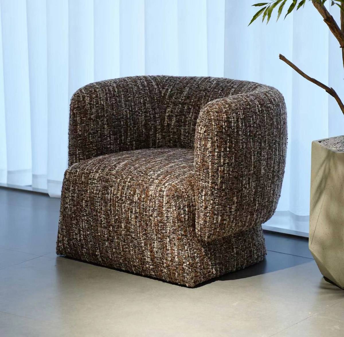 Lounge chair placed in a room setting with a plant and curtains