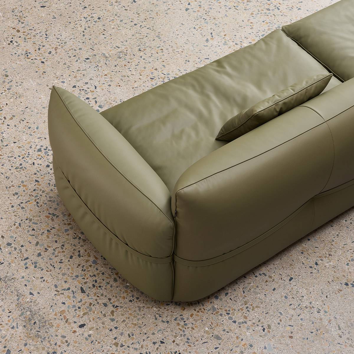 High-angle view of the sofa corner showing the seat cushion and throw pillow on a terrazzo floor