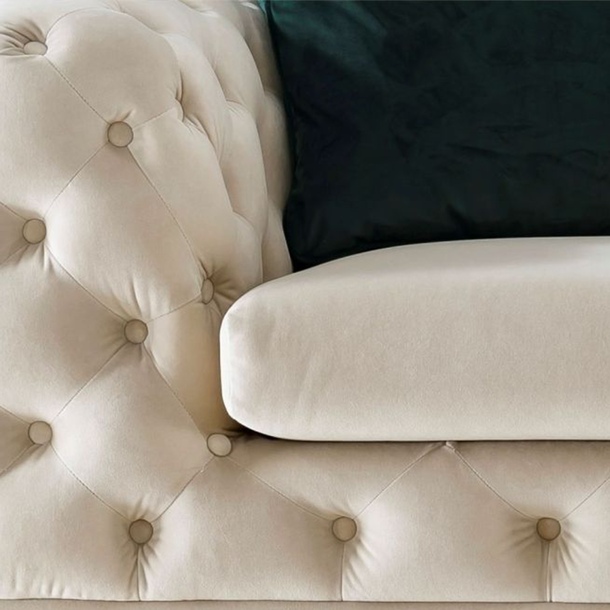 Close-up detail of the cream-colored tufted velvet sofa showing the button design and fabric texture