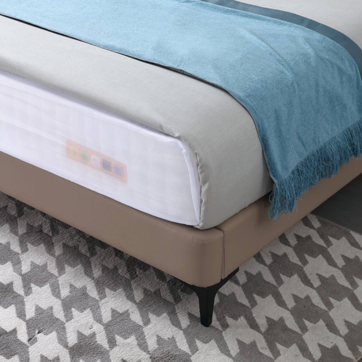 Close-up of the bed corner showing the leather frame and black leg