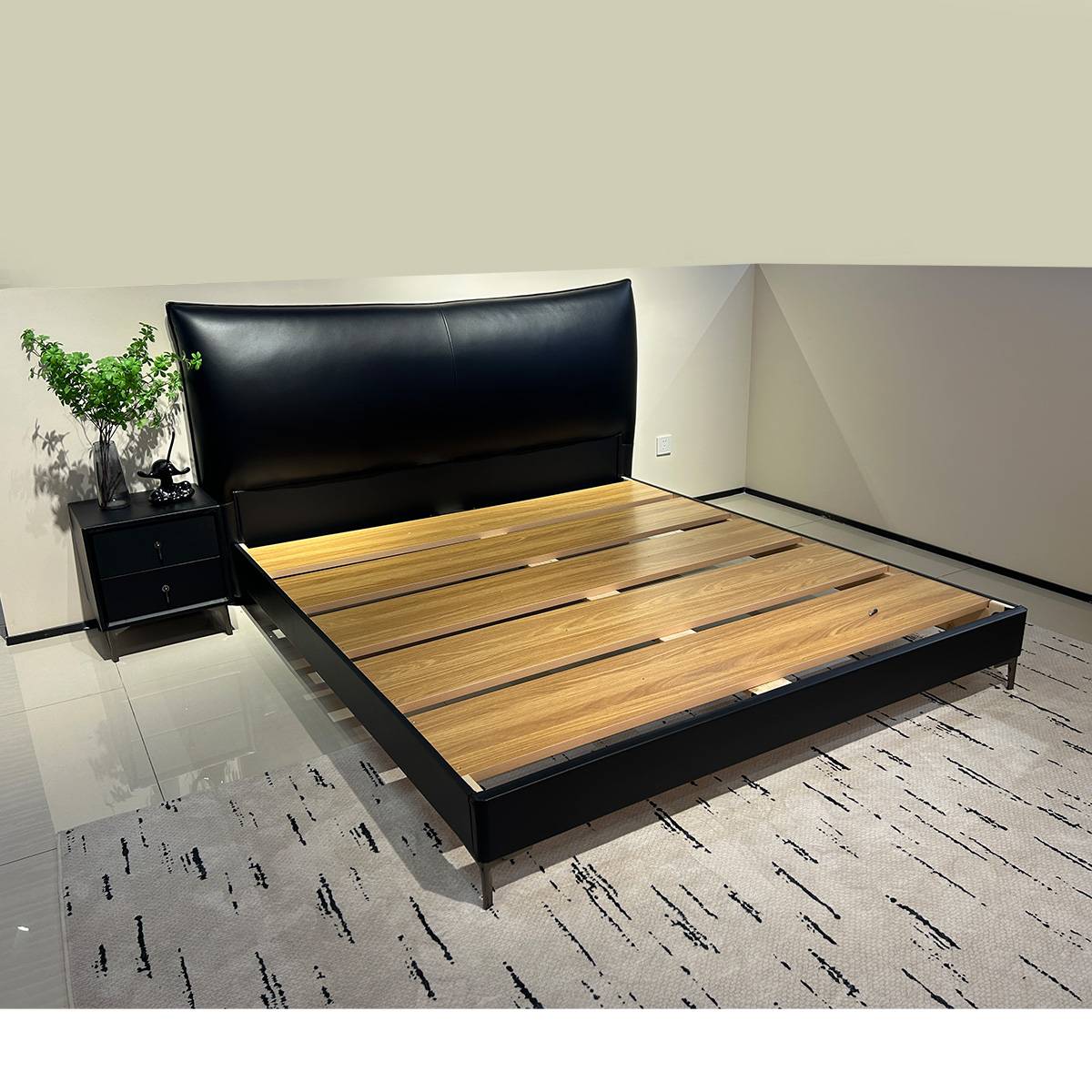 Full view of the black leather soft bed with wooden slats in a bedroom setting