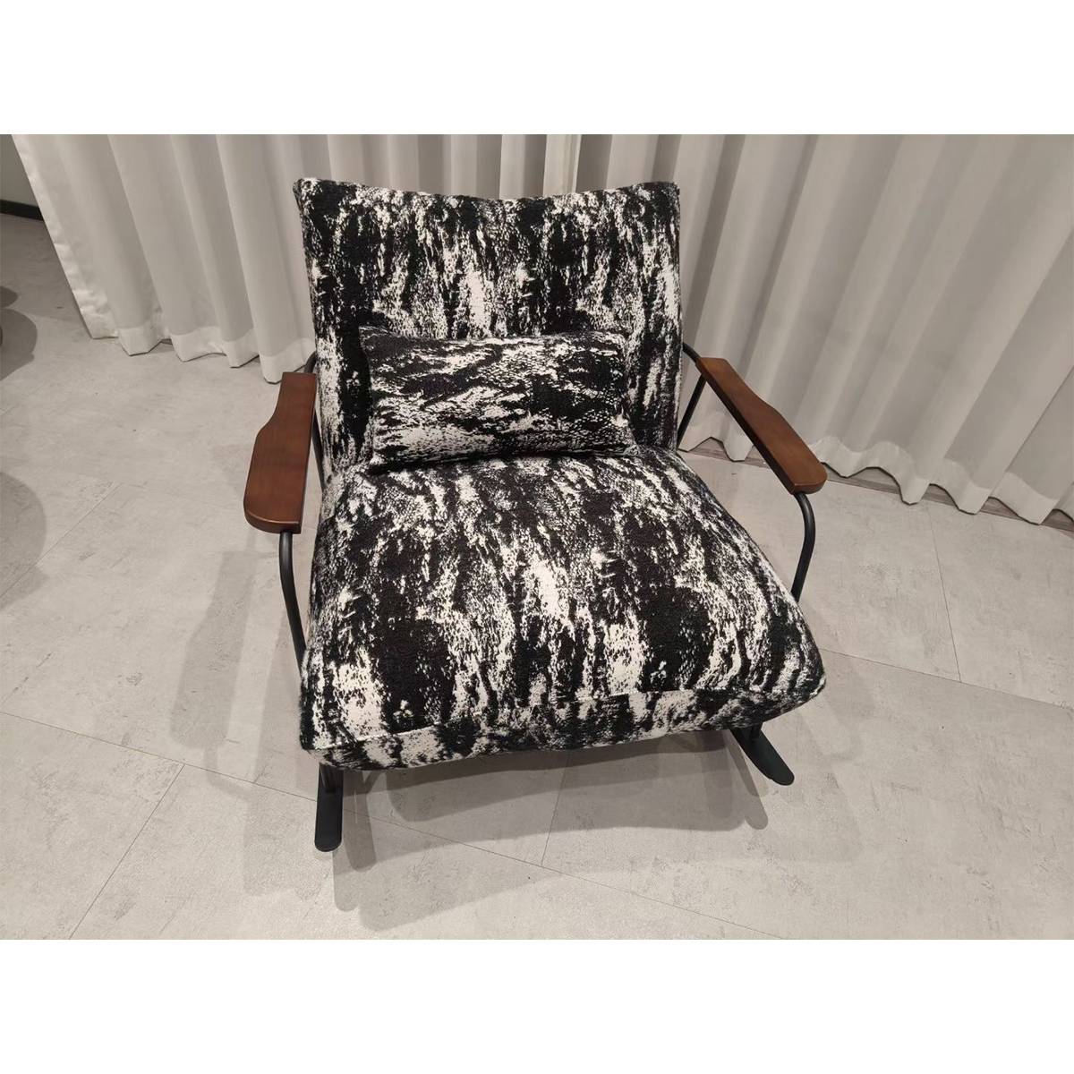 Close-up of a black and white patterned lounge chair with wooden armrests