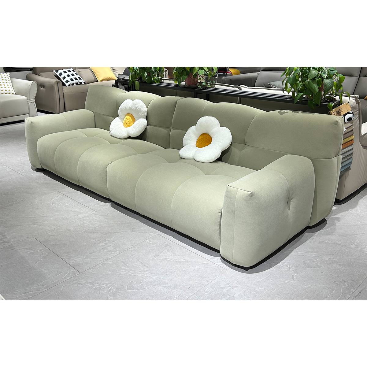 Close-up view of the light green Puff sofa armrest and seat cushion with a flower-shaped pillow