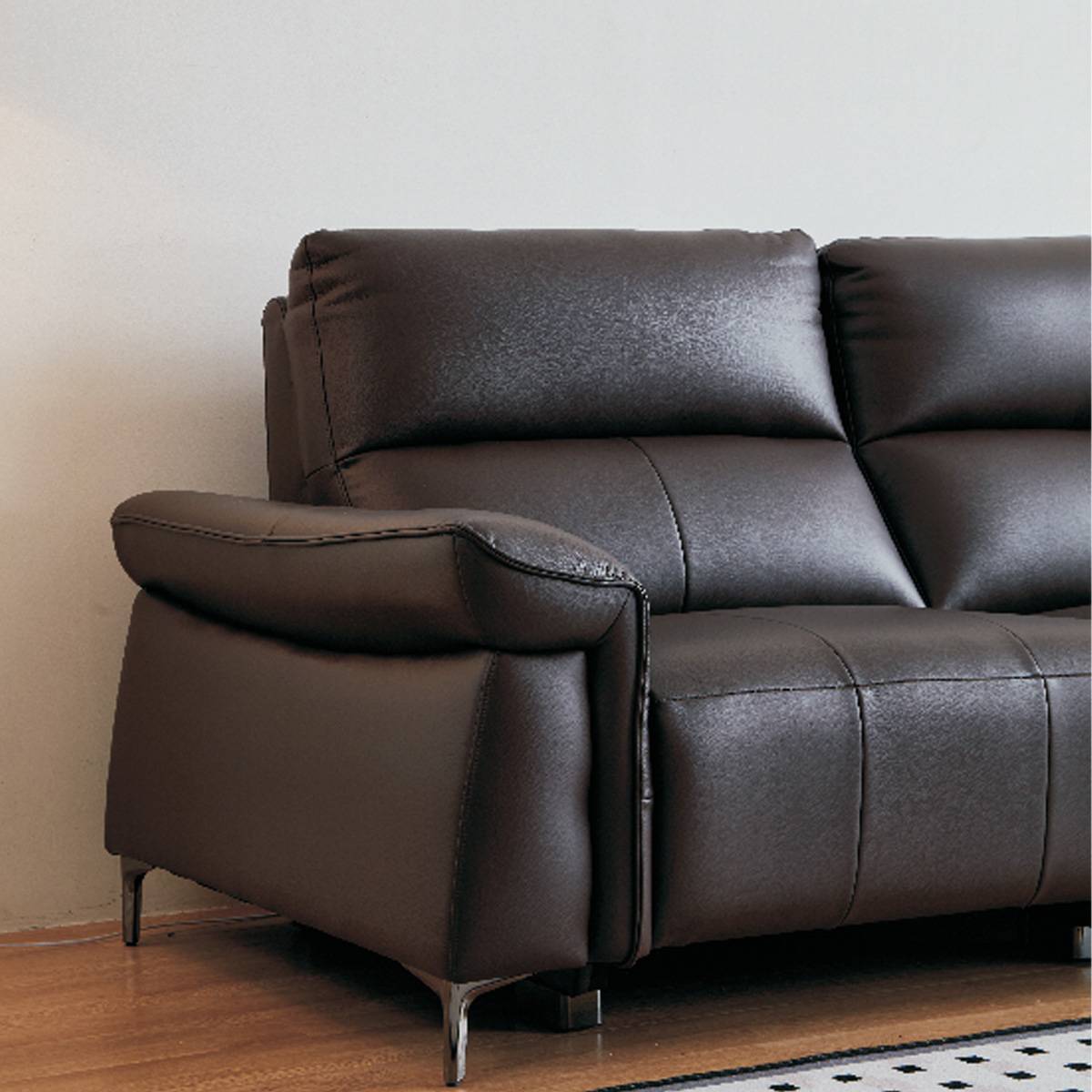 Close-up of the brown leather sofa armrest and back cushion showing texture and stitching details.