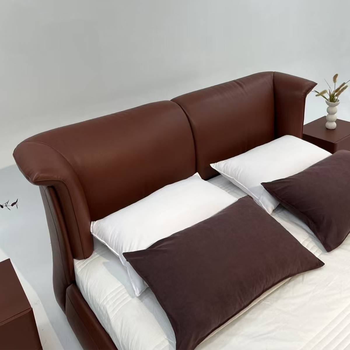 High angle view of brown leather bed with white and brown pillows