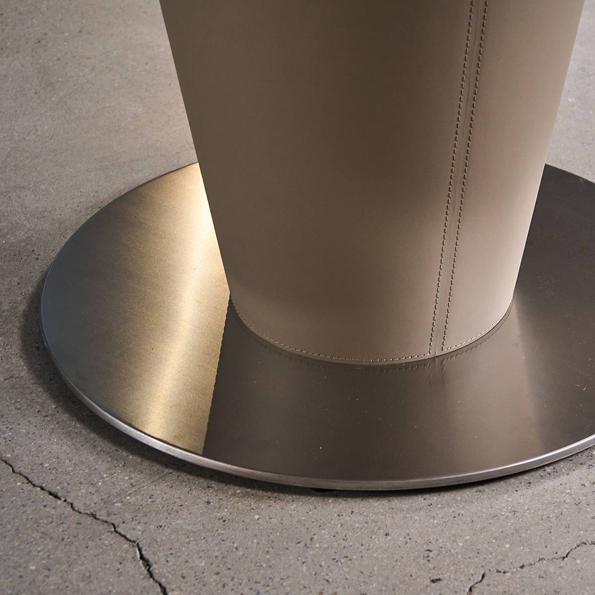 Close-up detail of the saddle leather wrapped pedestal base and metal foot.
