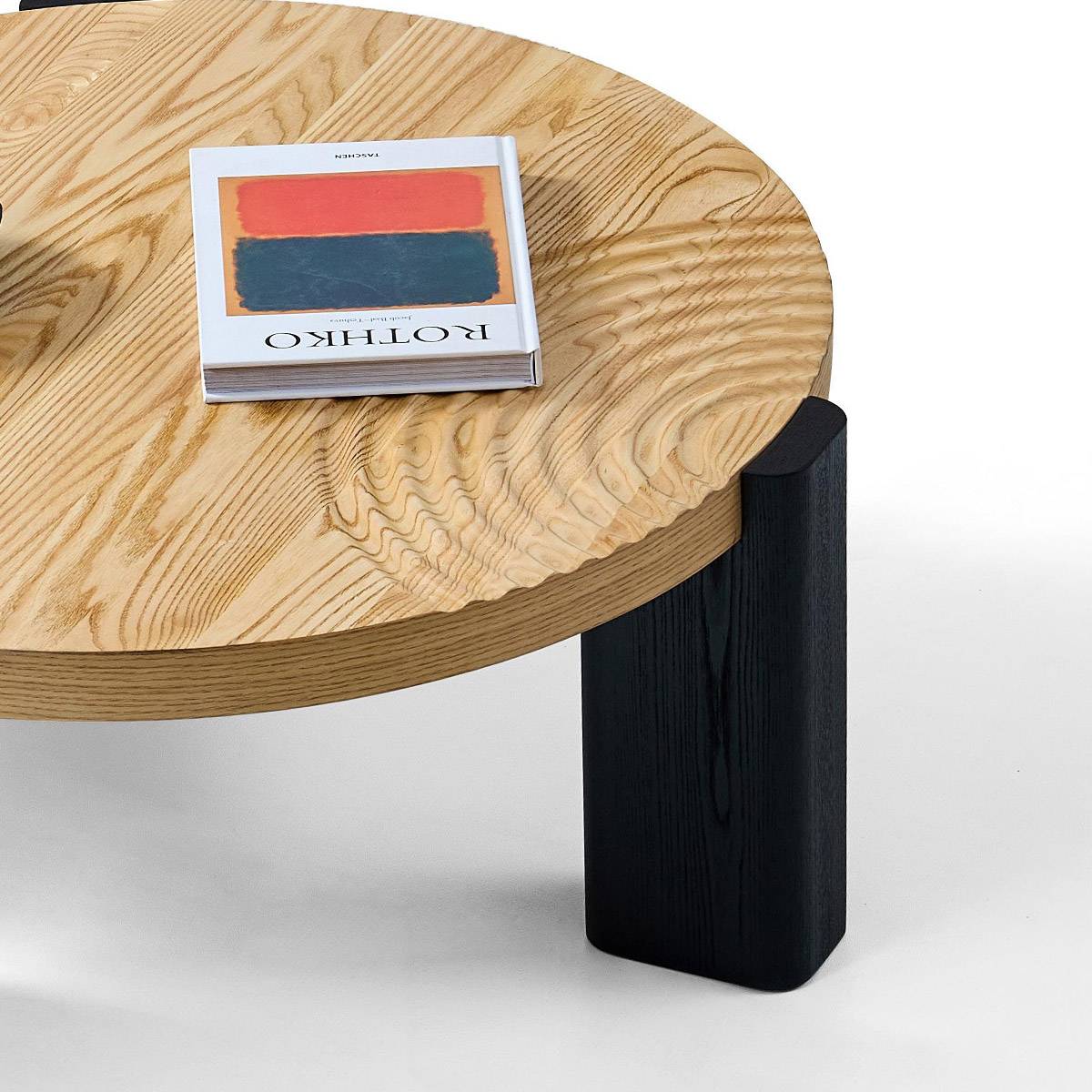 Close-up detail of the ash wood grain on the table top and the black wooden leg