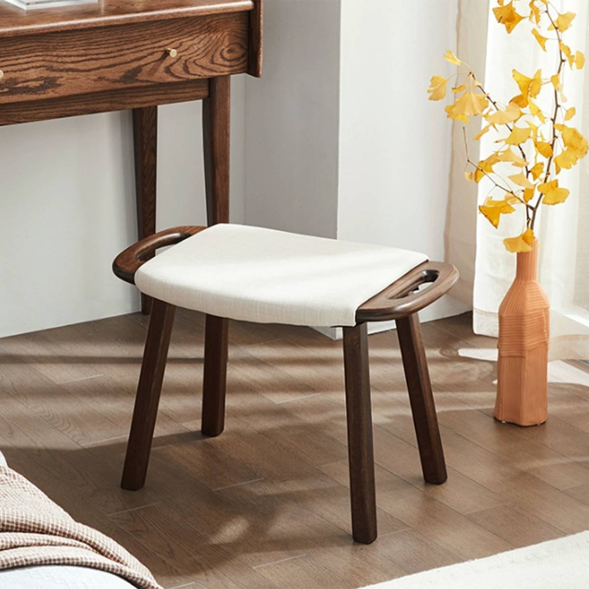 Dark wood finish version of the vanity stool placed next to a desk and vase