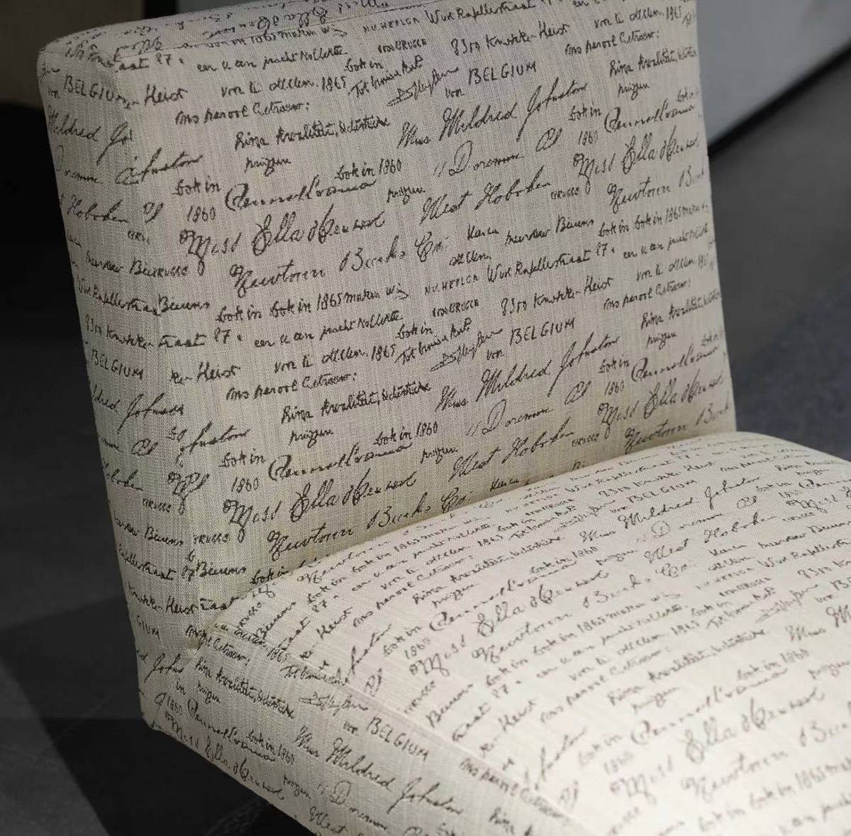 Close-up detail of the fabric texture and script pattern on the chair's backrest