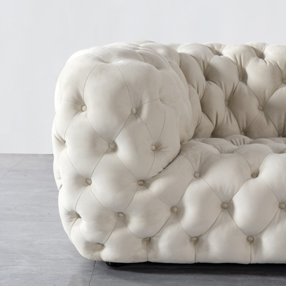 Side profile view of the sofa showing the rounded armrest and tufted detailing