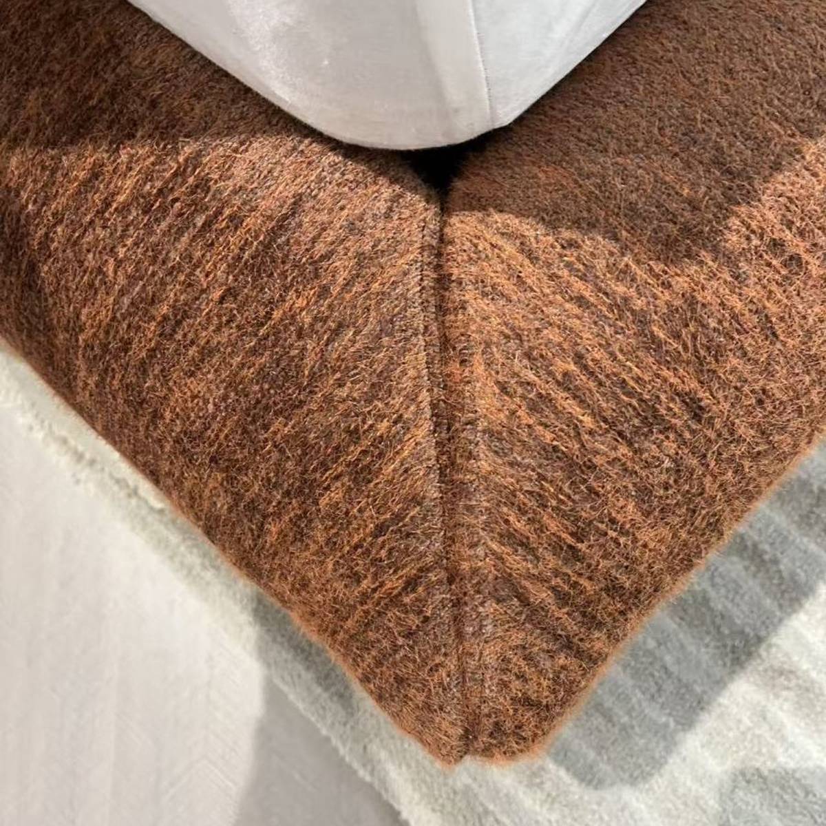 Close-up of the corner stitching and chenille fabric texture on the bed