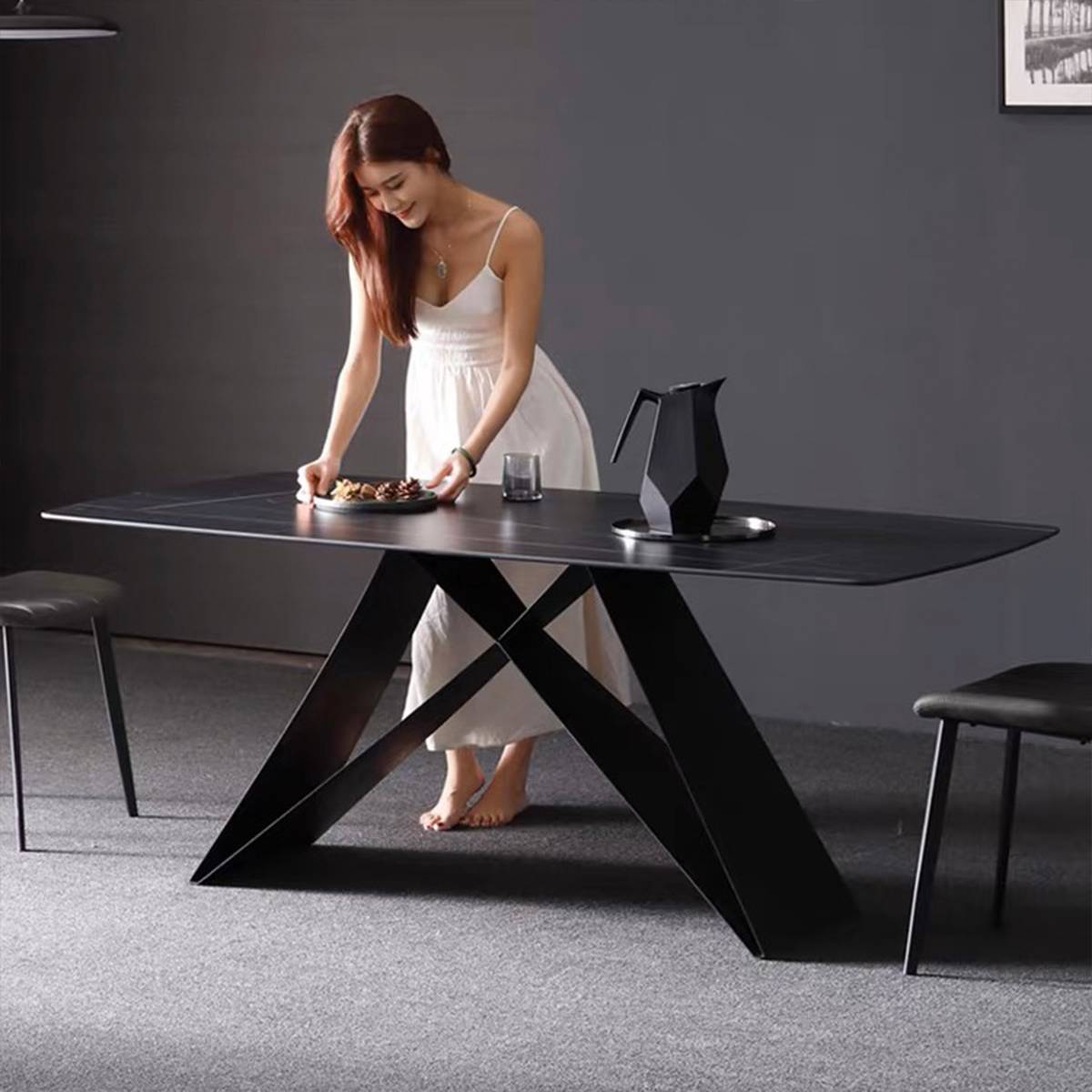 Model placing a plate on a dark grey dining table with a geometric black pitcher