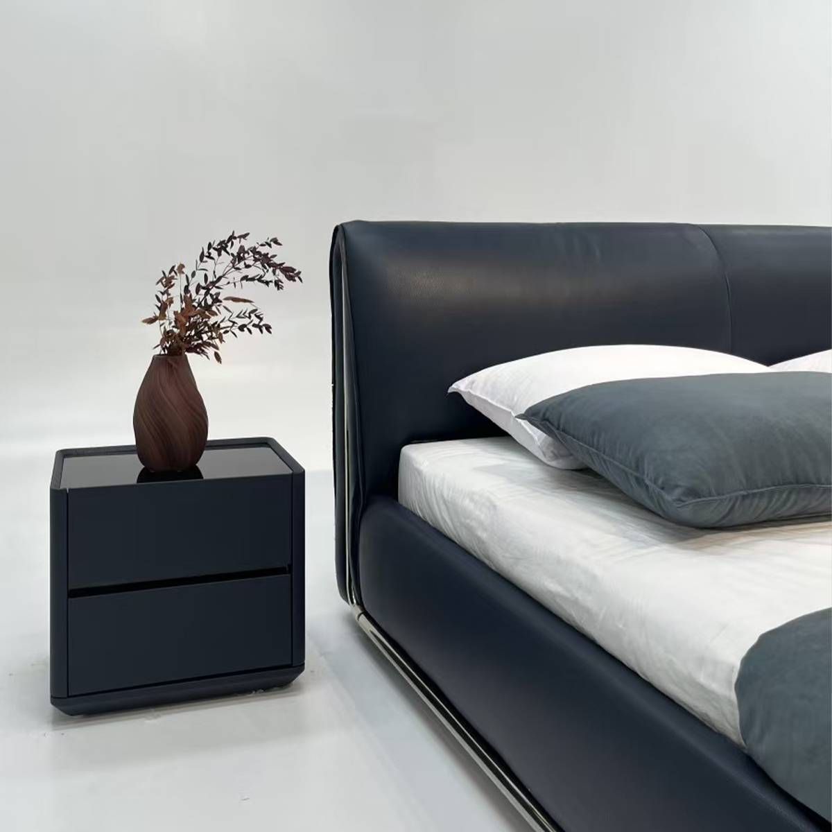 Side view of a dark blue leather bed with a metal base and white bedding
