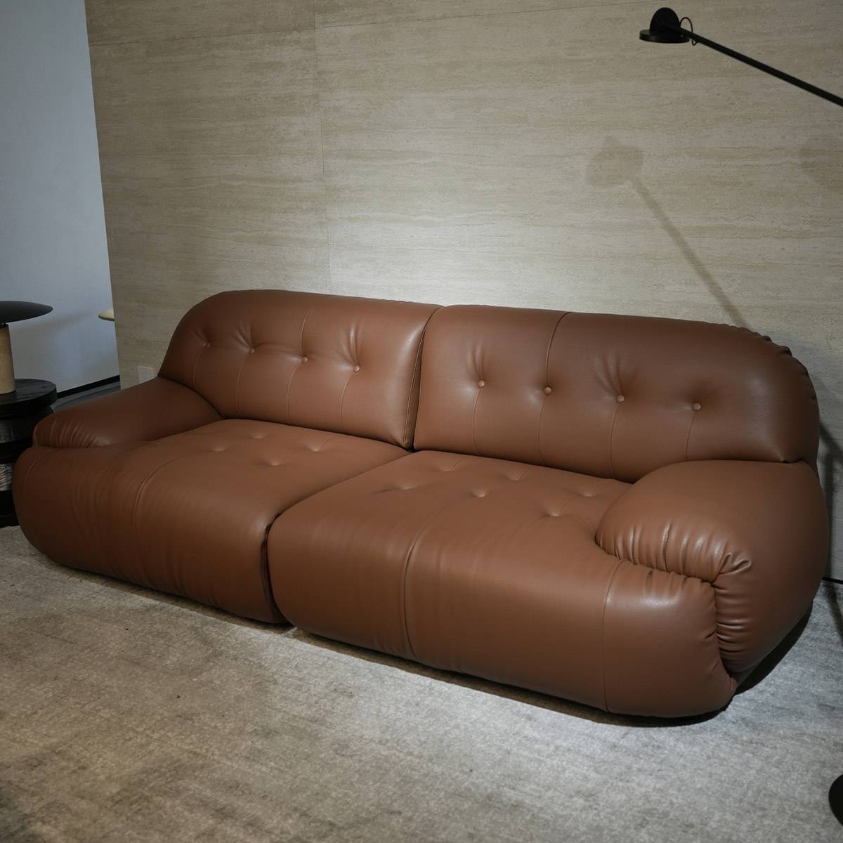 Full view of the brown leather sofa against a textured wall