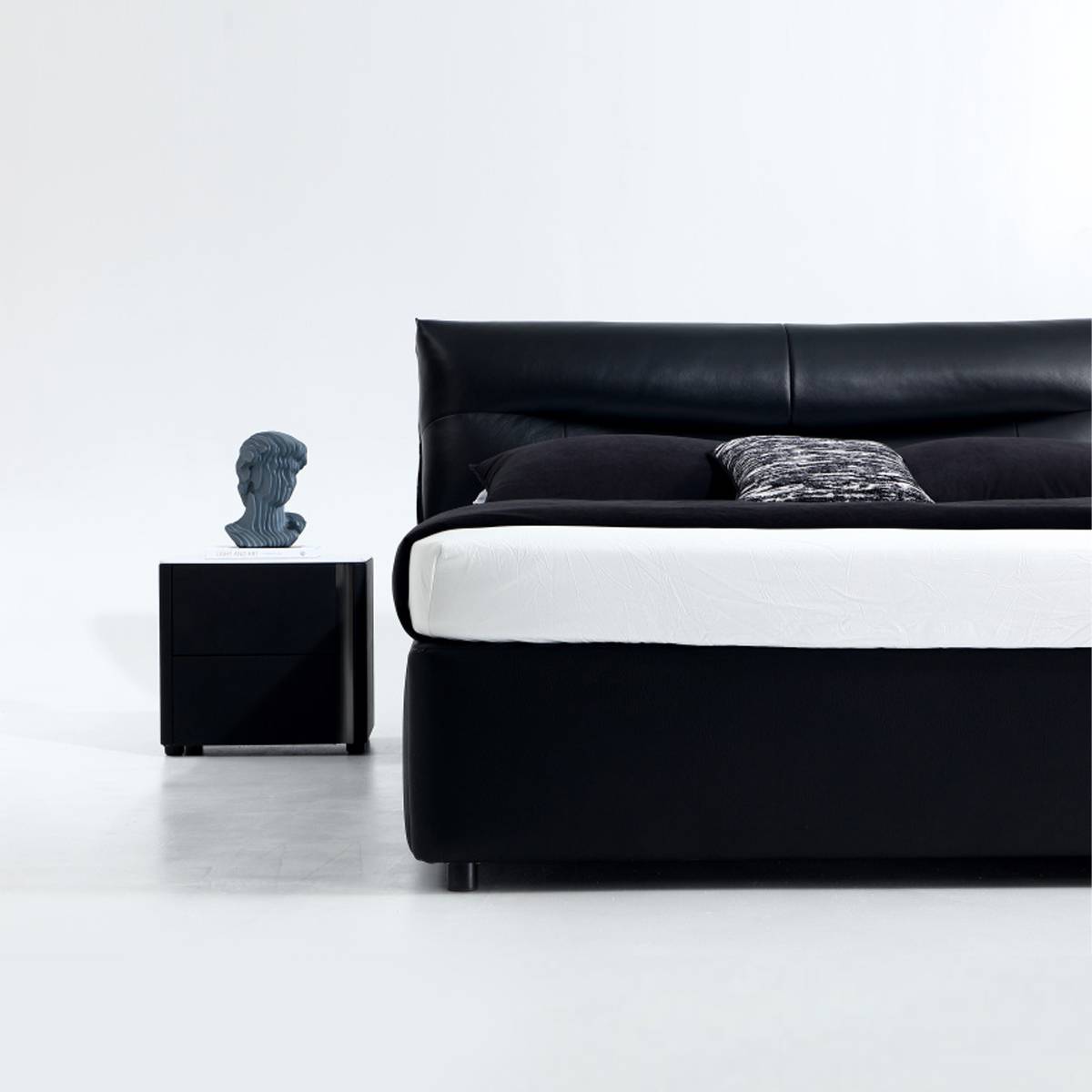 Close-up view of the bed frame and a black bedside table with a decorative bust.