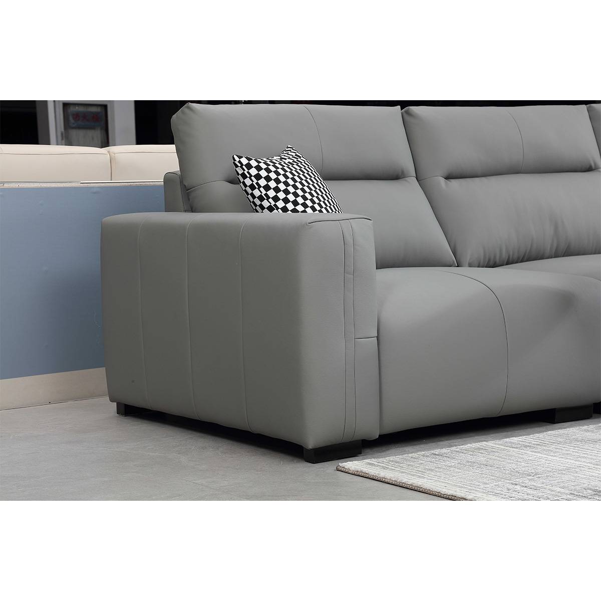 Close-up of the sofa armrest and base showing the solid wood legs and upholstery stitching.