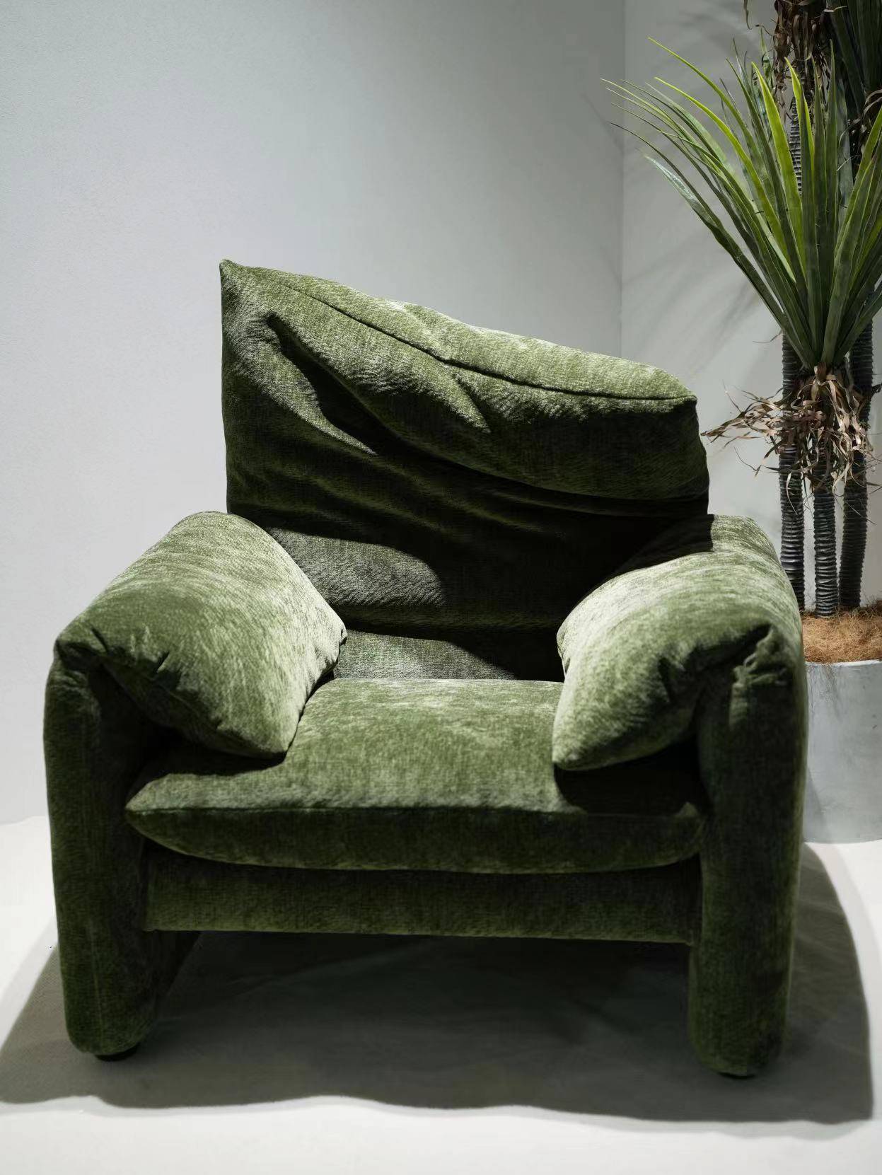 Front view of the green velvet lounge chair with plant