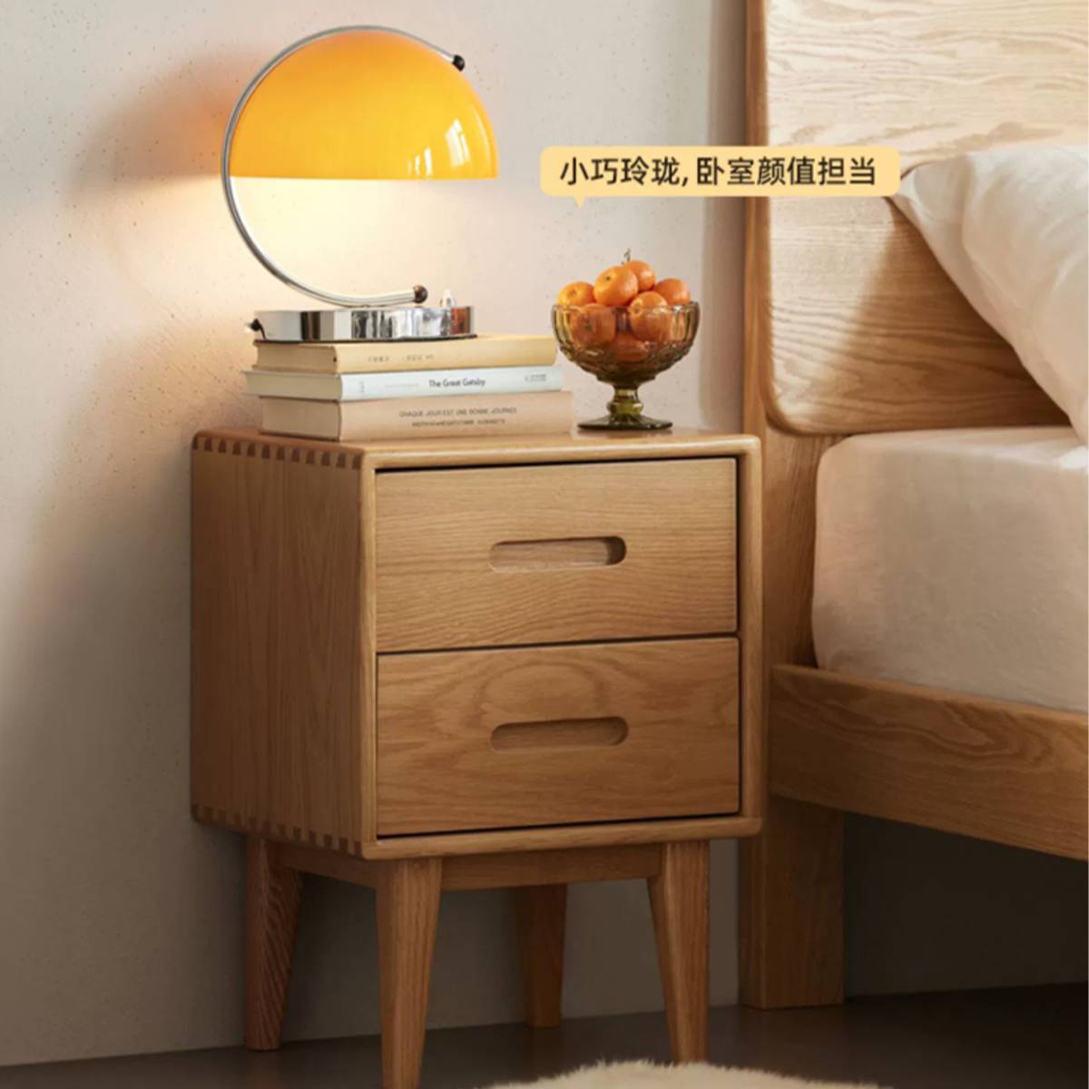 Bedside table placed next to a bed with a lamp and fruit bowl