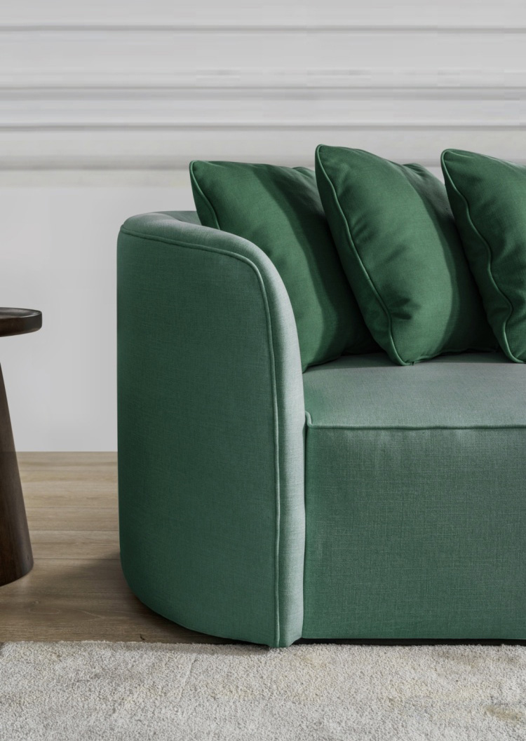 Close-up of green curved sofa armrest and cushions