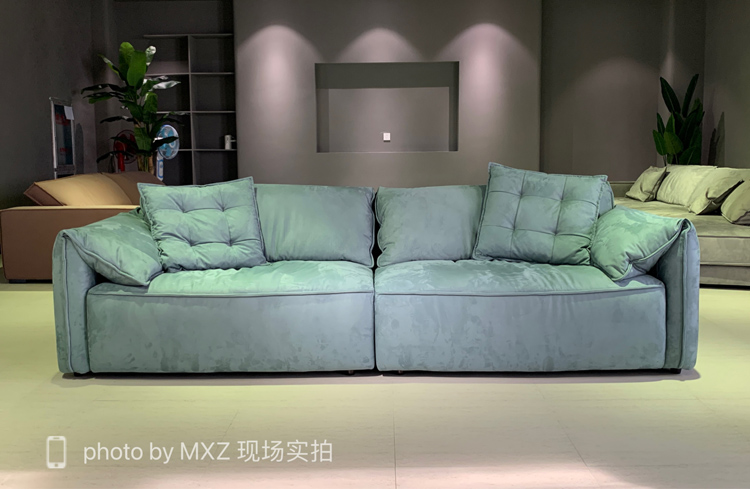 Full view of the teal elephant ear sofa displayed in a showroom setting.