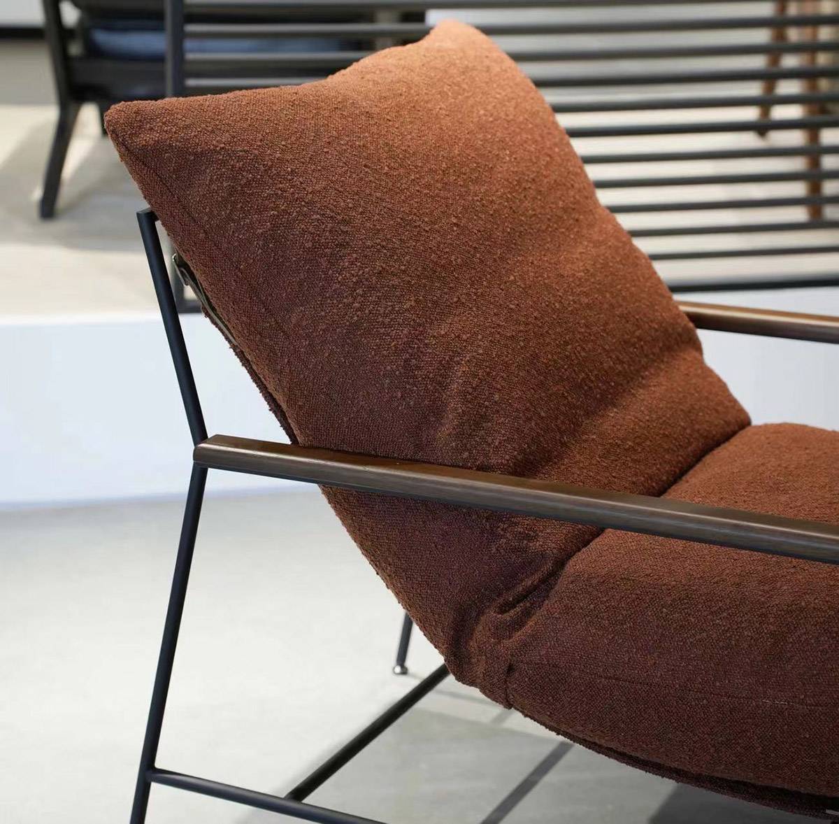 Close-up of the brown fabric back cushion and metal frame of the lounge chair