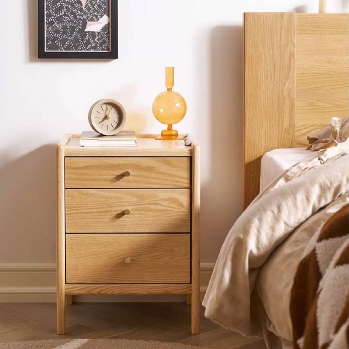 Front view of the wooden bedside table with clock and lamp on top