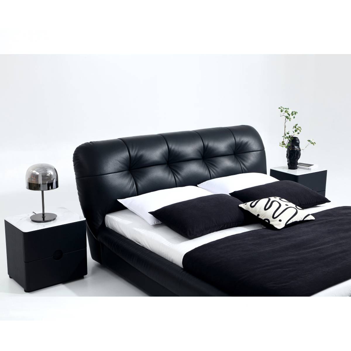 Full view of black leather tufted bed with bedside tables