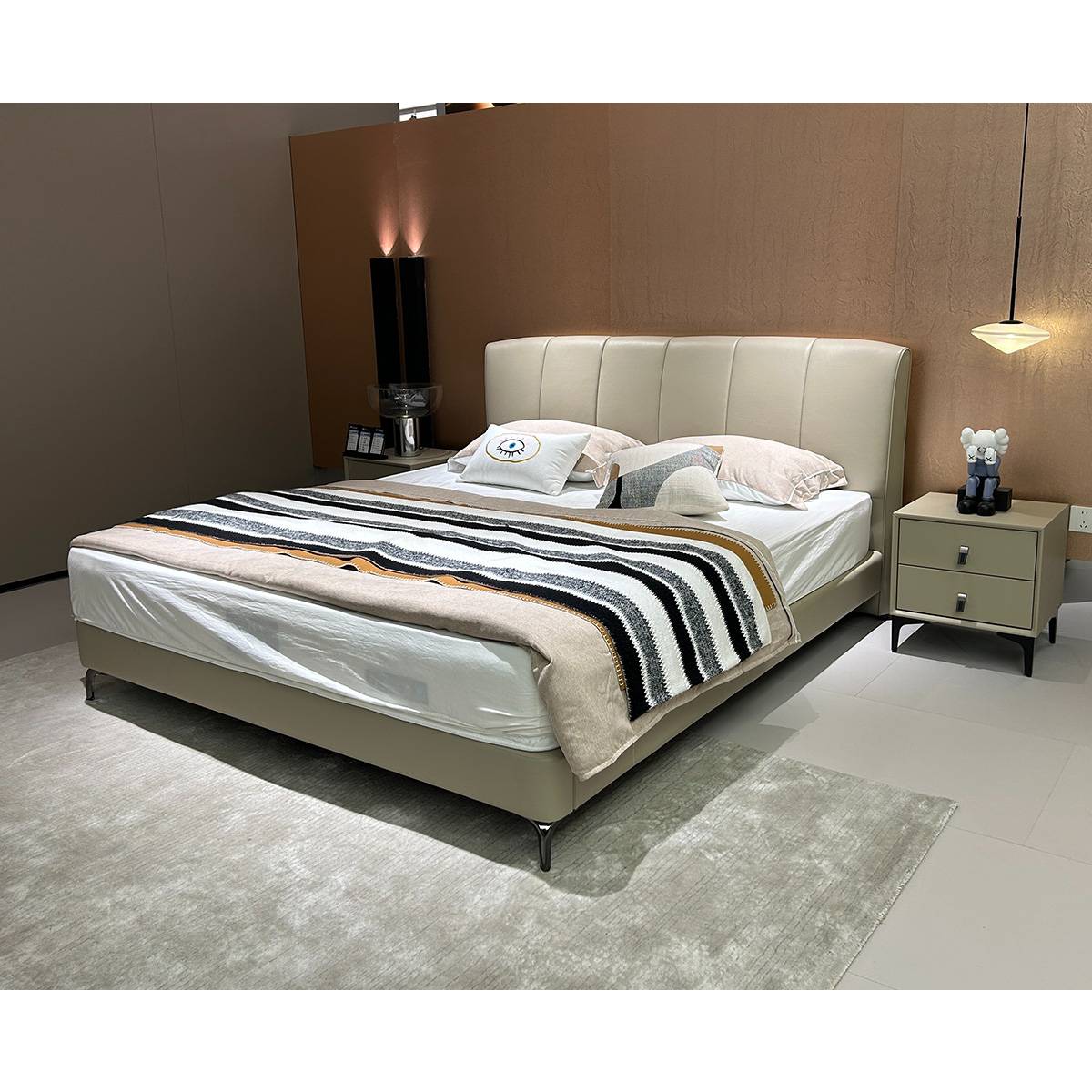 Front view of the beige leather bed with striped throw blanket
