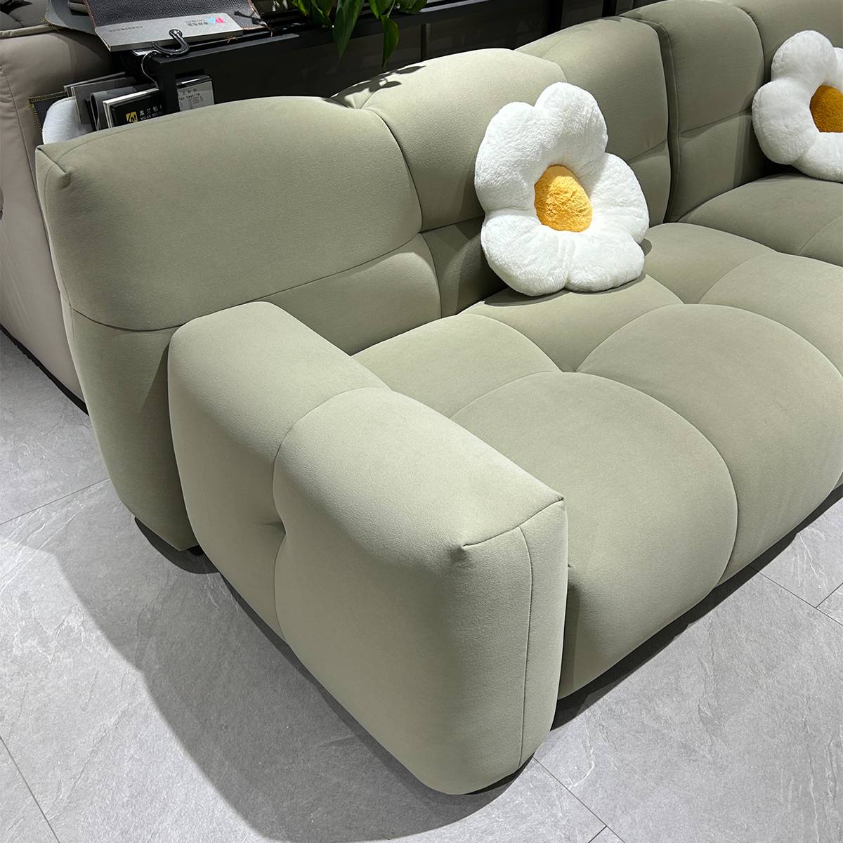 Side view of the light green Puff sofa showing the backrest and seat cushions with a flower-shaped pillow